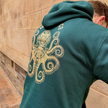 Load image into Gallery viewer, Person wearing a teal hoodie with an octopus design on the back, standing against a stone wall.